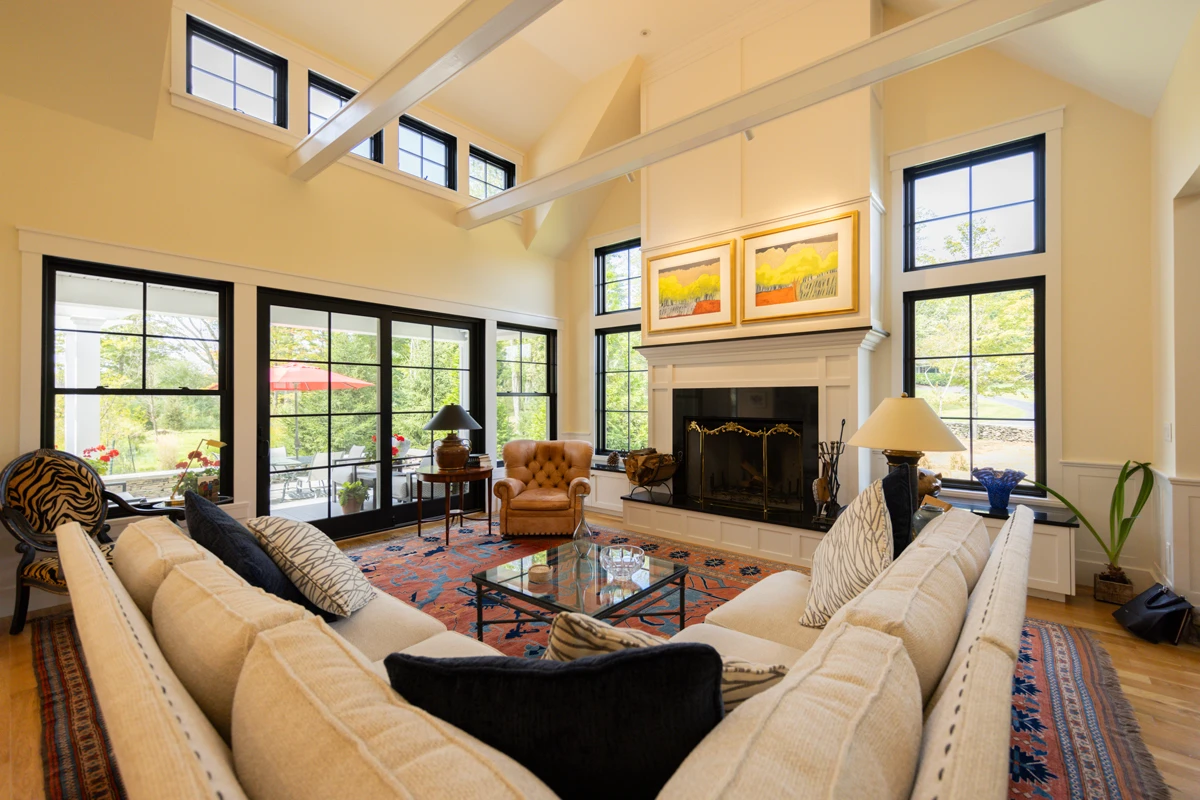 A light-filled living room with a fireplace, framed art and an oriental rug