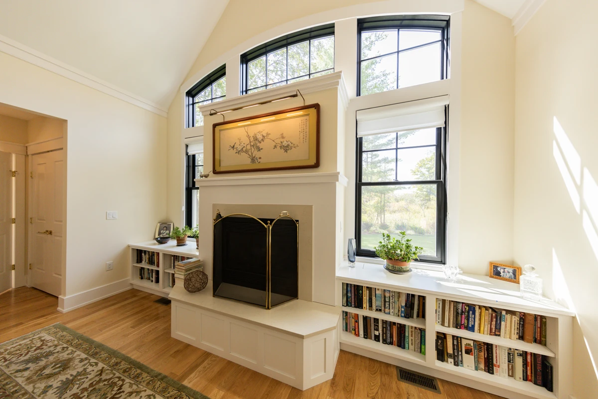 Black windows set in white-painted trim beside a fireplace