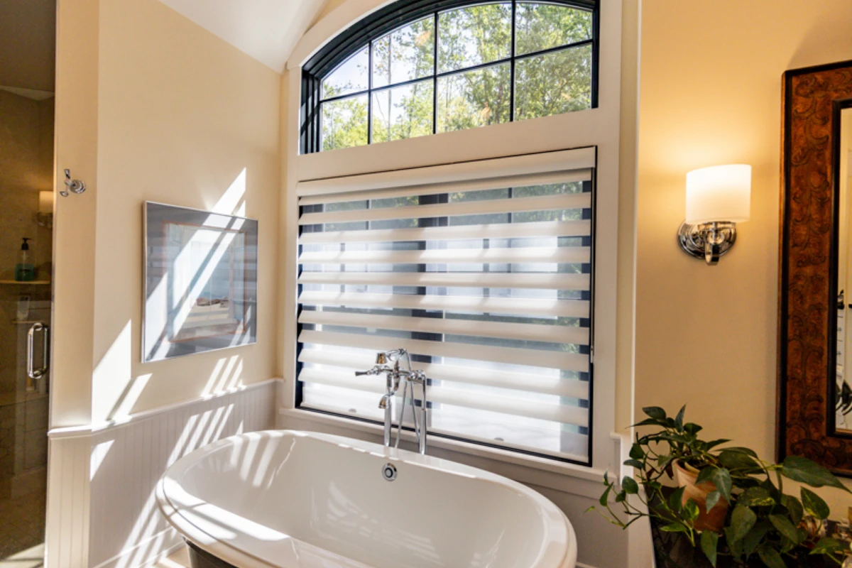 A freestanding tub and filler under an arched window in a new home