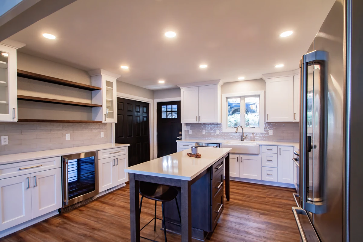 A white kitchen with a navy island and open shelving in a lake house