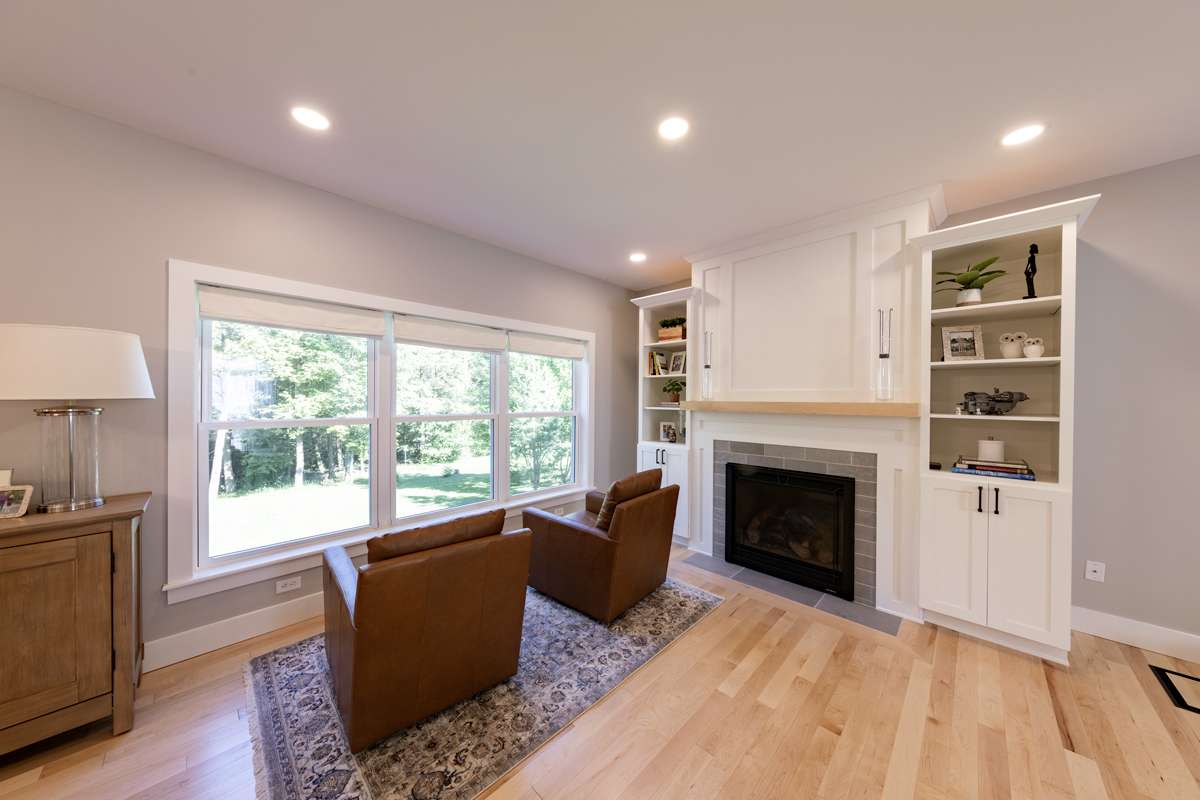 A living room fireplace with white built-in cabinets and shelves beside it