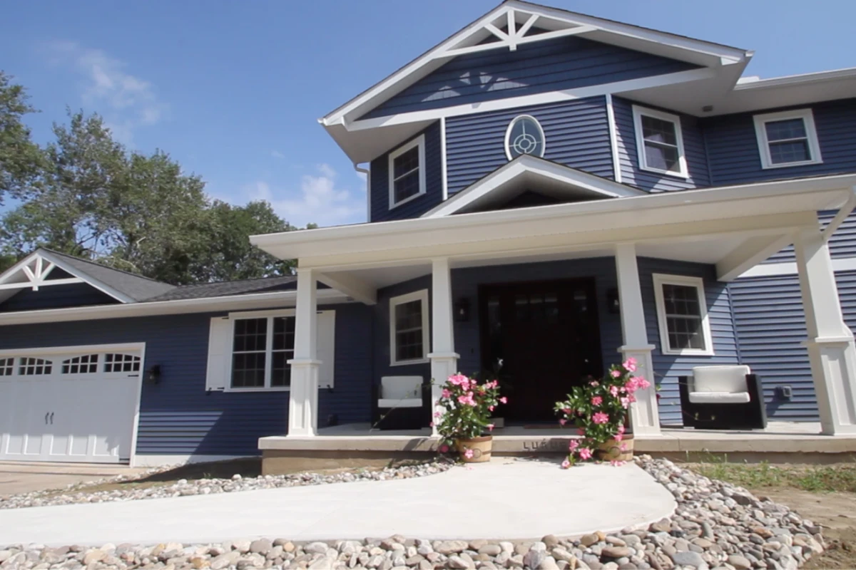 A two-story blue Craftsman house with a white front porch and tapered columns