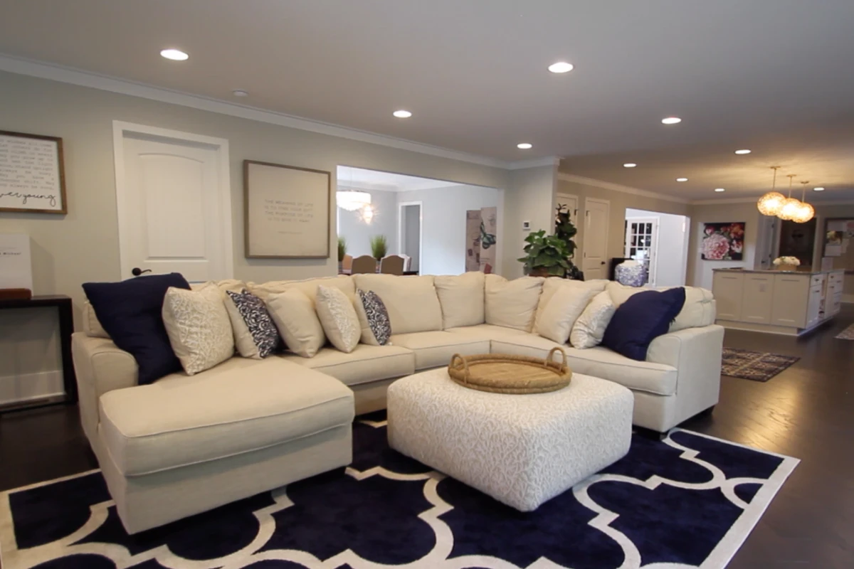 A living room with a cream sectional, open to the kitchen and dining room behind it