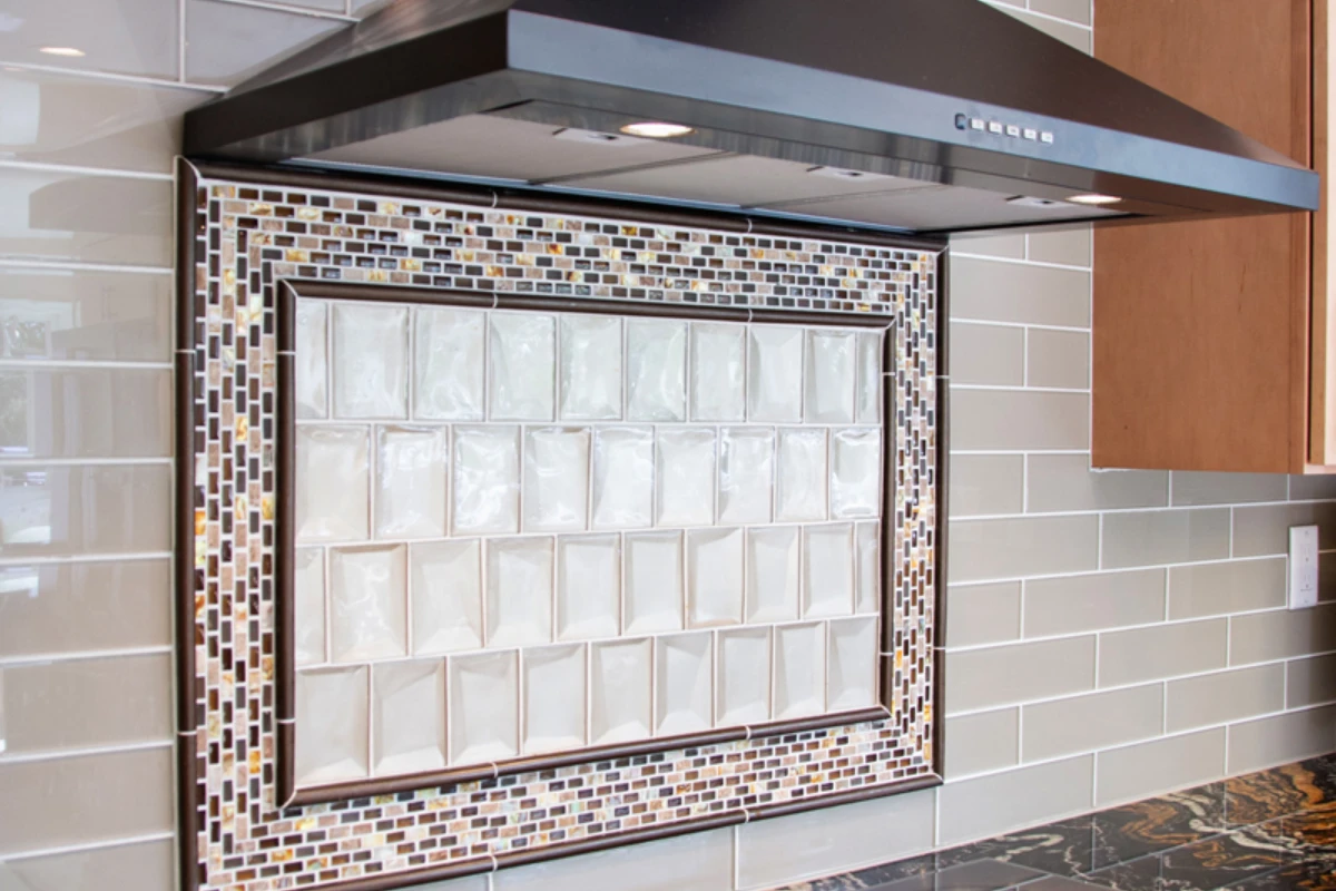 A framed glass mosaic backsplash behind a kitchen range hood