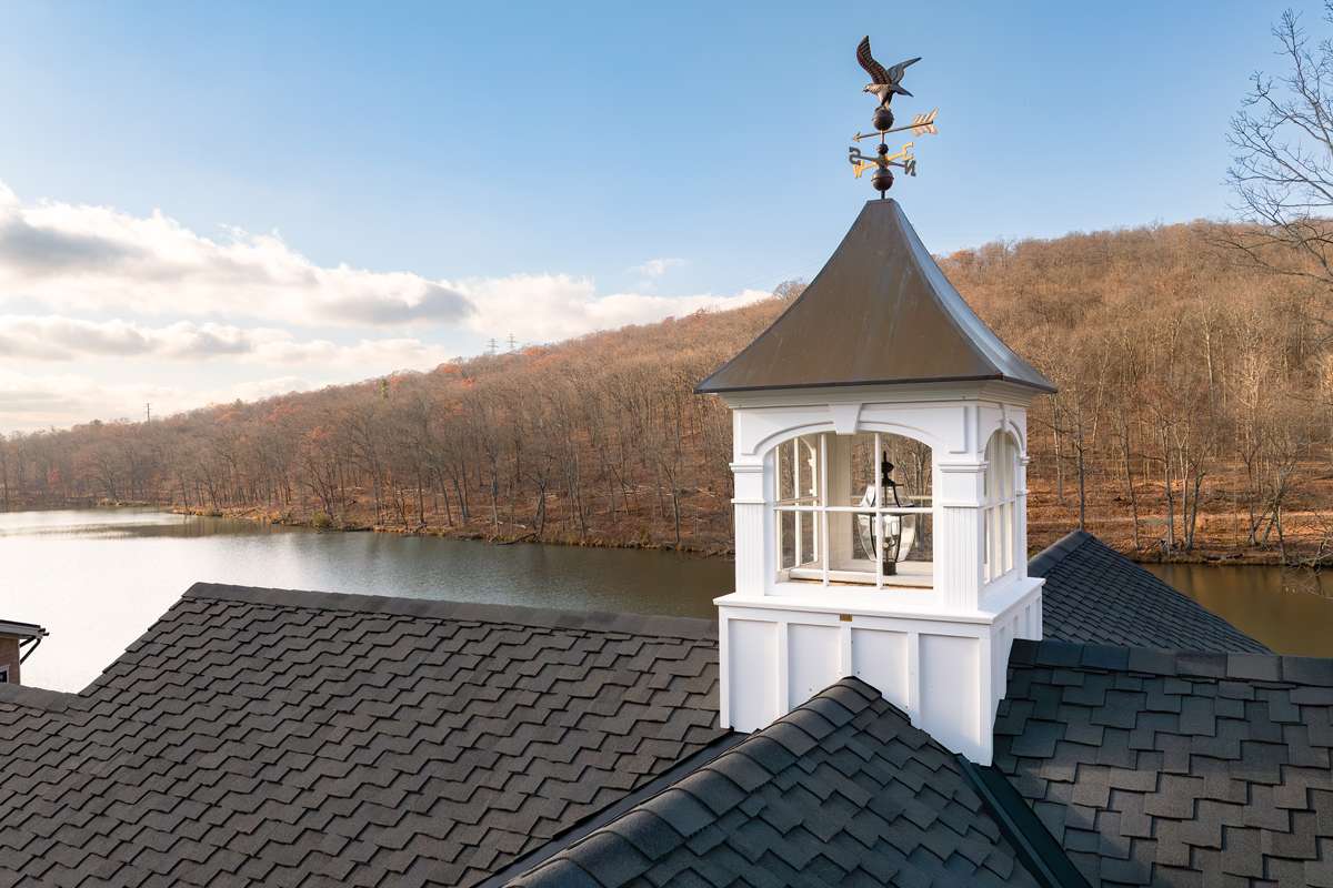 A cupola with a weathervane on a shingle roof
