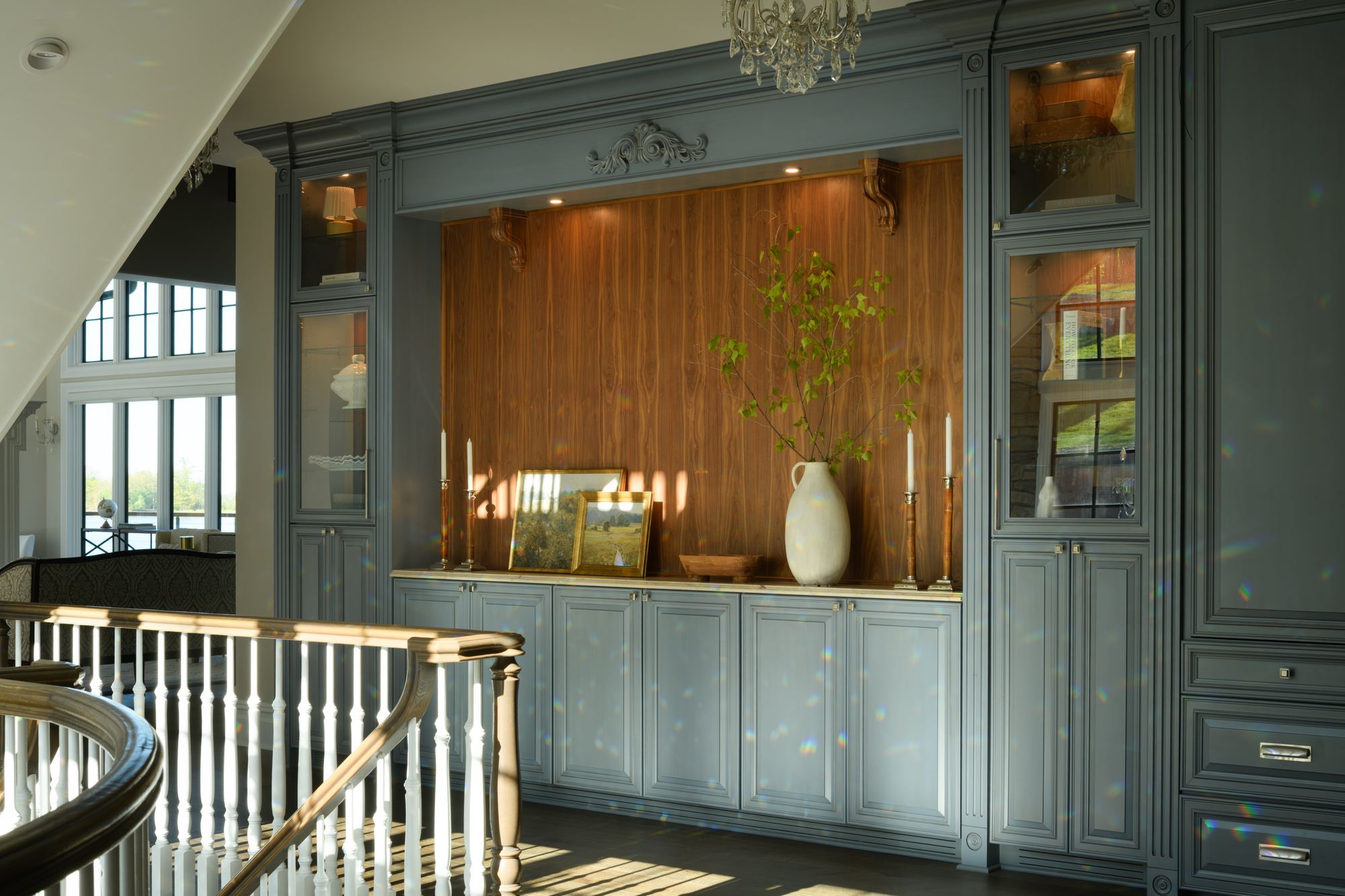 Blue-gray built-in cabinetry with a wood-lined niche at the top of the stairs