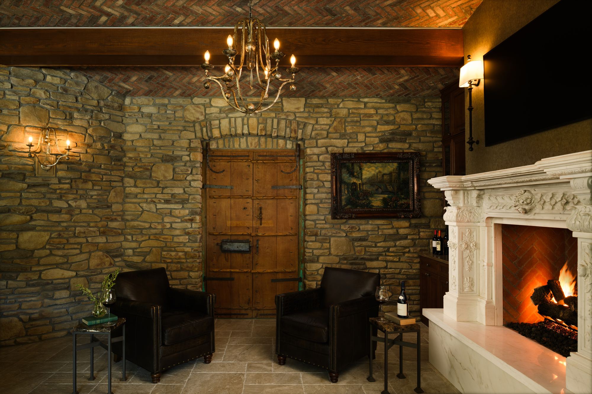 Stone-walled wine cellar lounge with a carved fireplace and a plank door