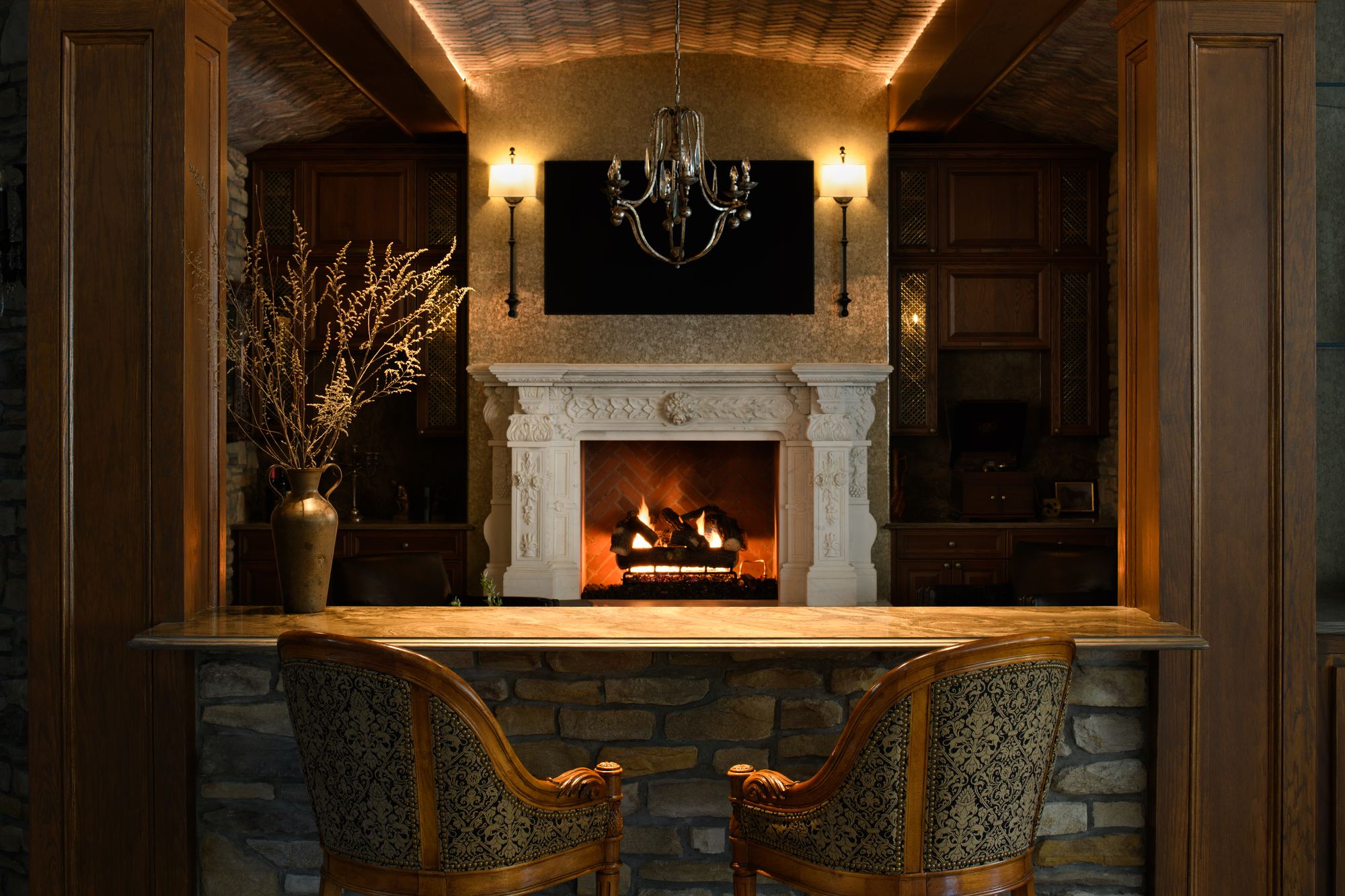 Bar seating facing a carved stone fireplace in the lower level