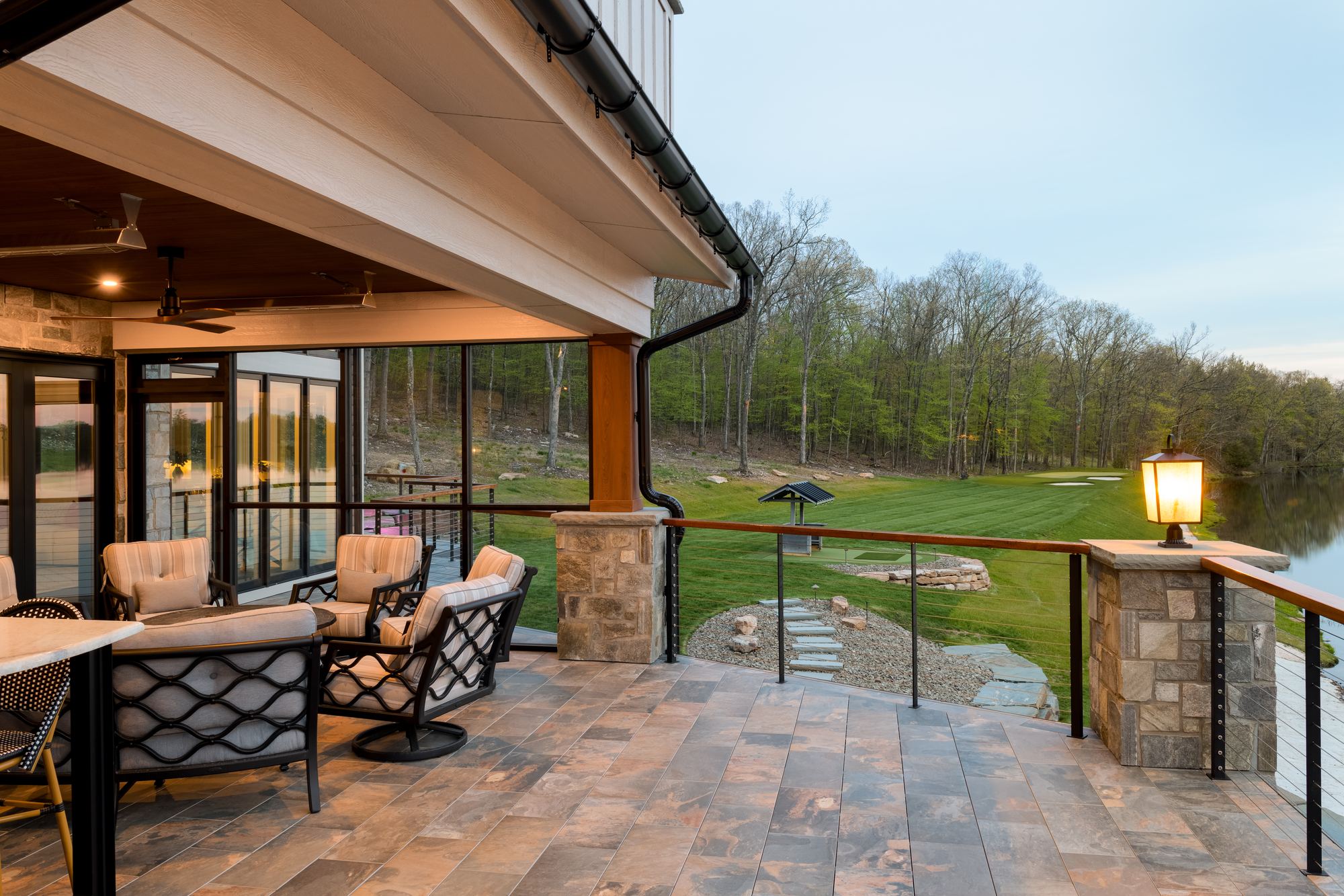 Covered patio seating with stone piers and lanterns along the lawn