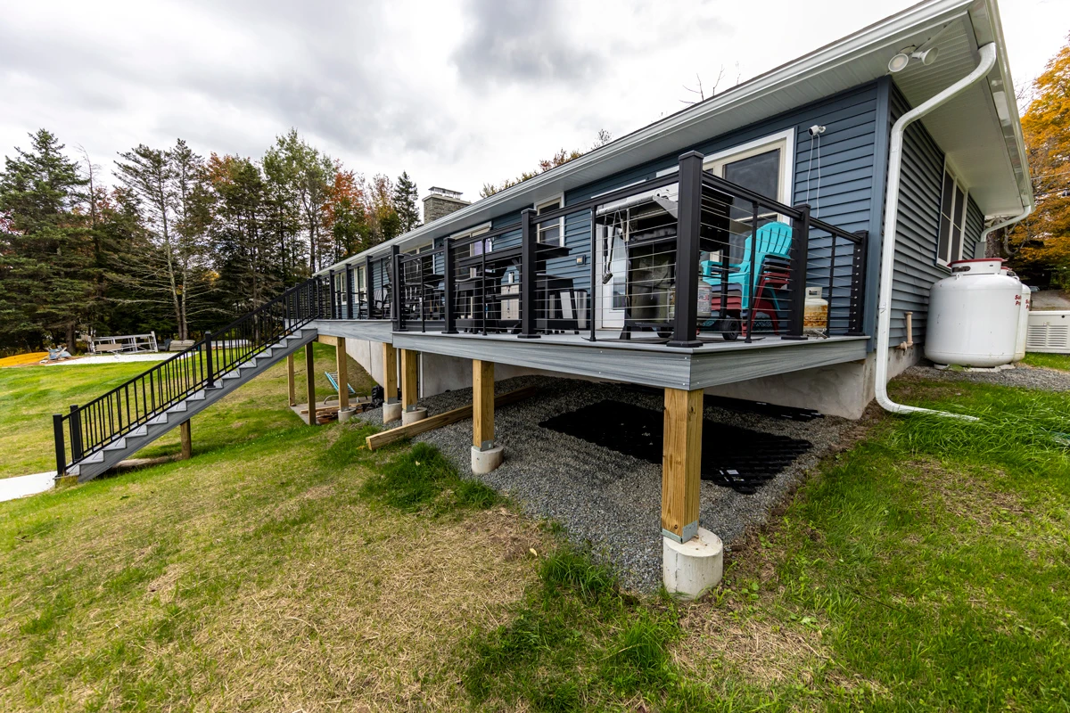 A raised composite deck on posts with black railings