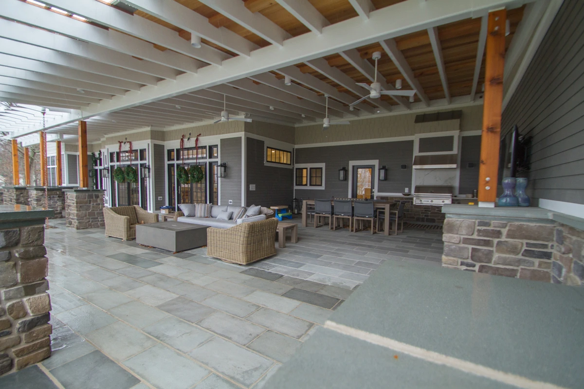 A covered outdoor room with stone piers, deep sofas and a television