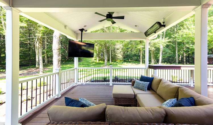 A covered deck with a ceiling fan, TV and heaters