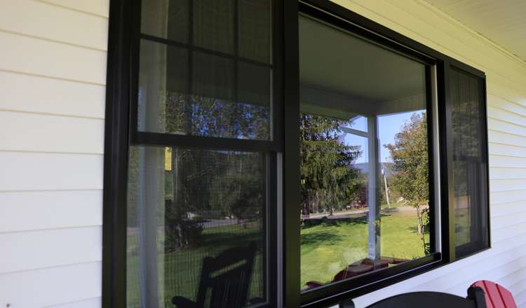 A new black-framed window set in white siding