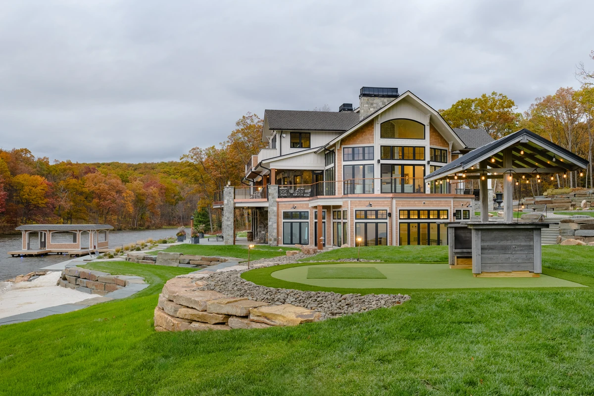 A lakefront home set into a hillside, with boulders set into the lawn