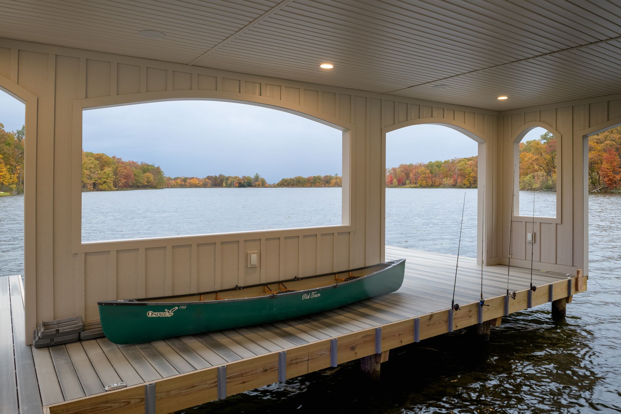 Covered boathouse slip with arched openings and a green canoe