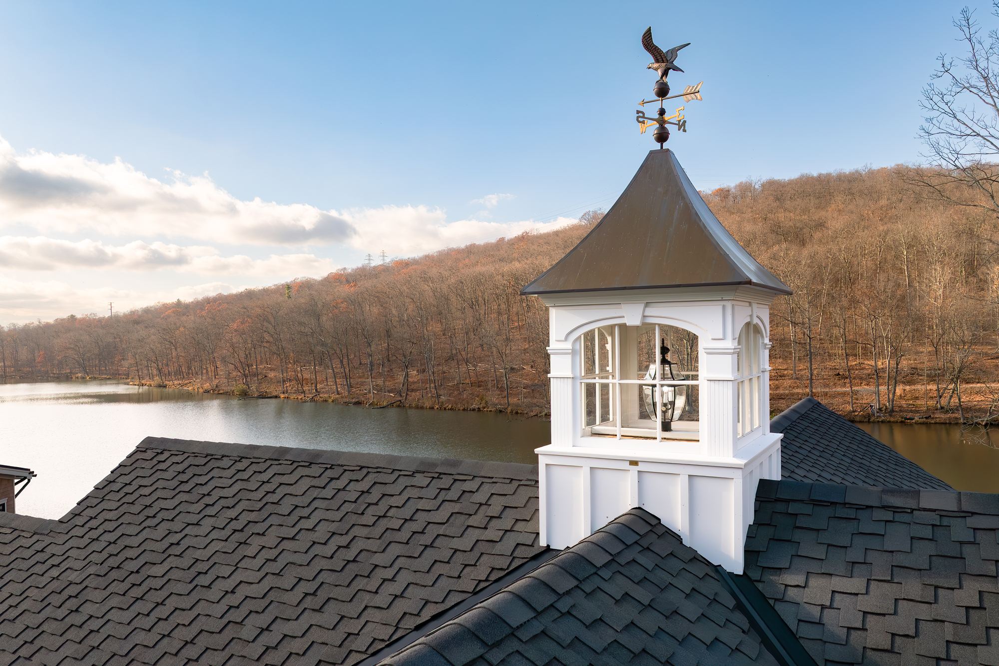 White cupola with a weathervane on the roof, the lake behind it