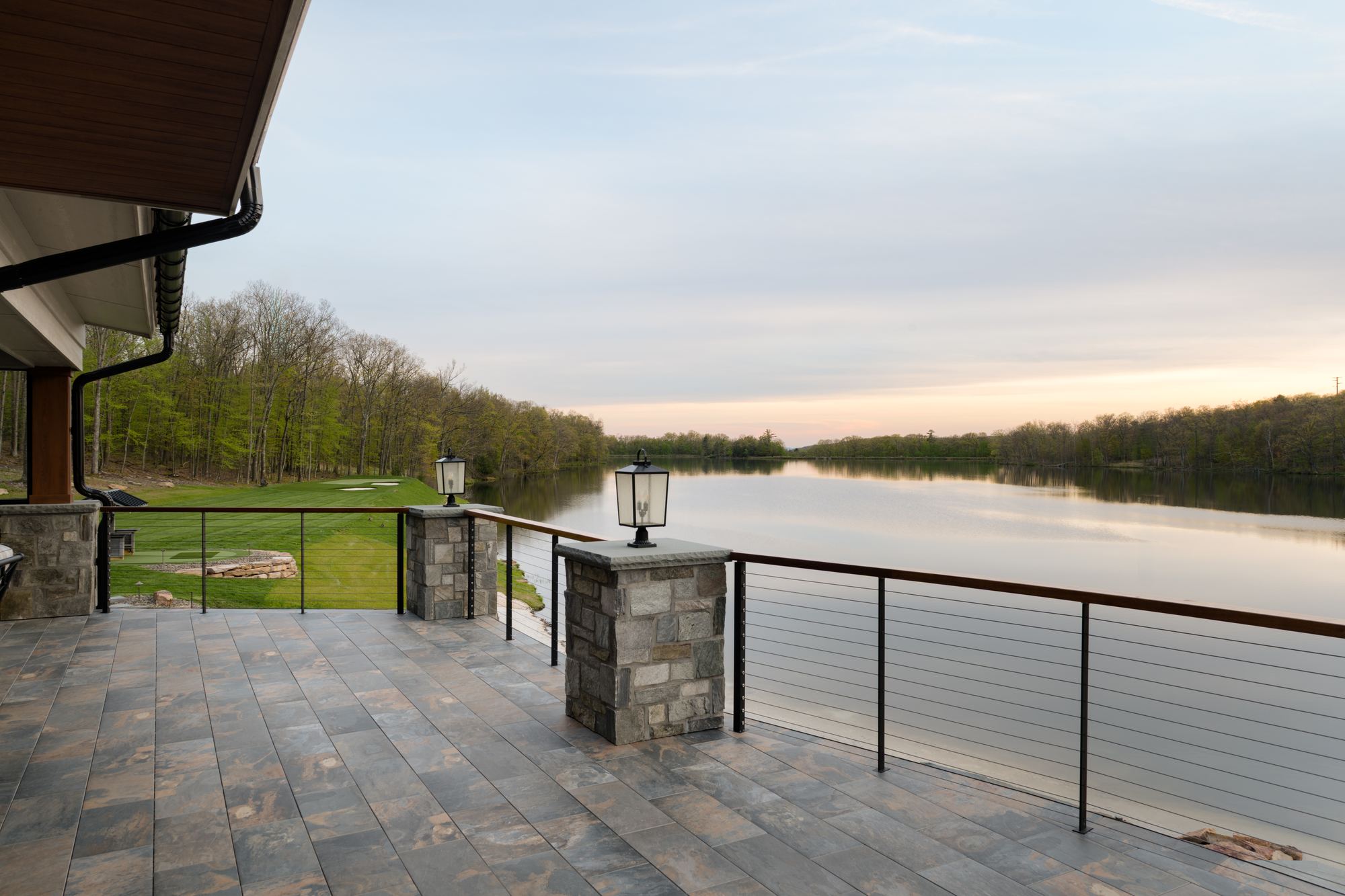 Stone patio with lantern-topped piers and cable railing along the lakefront