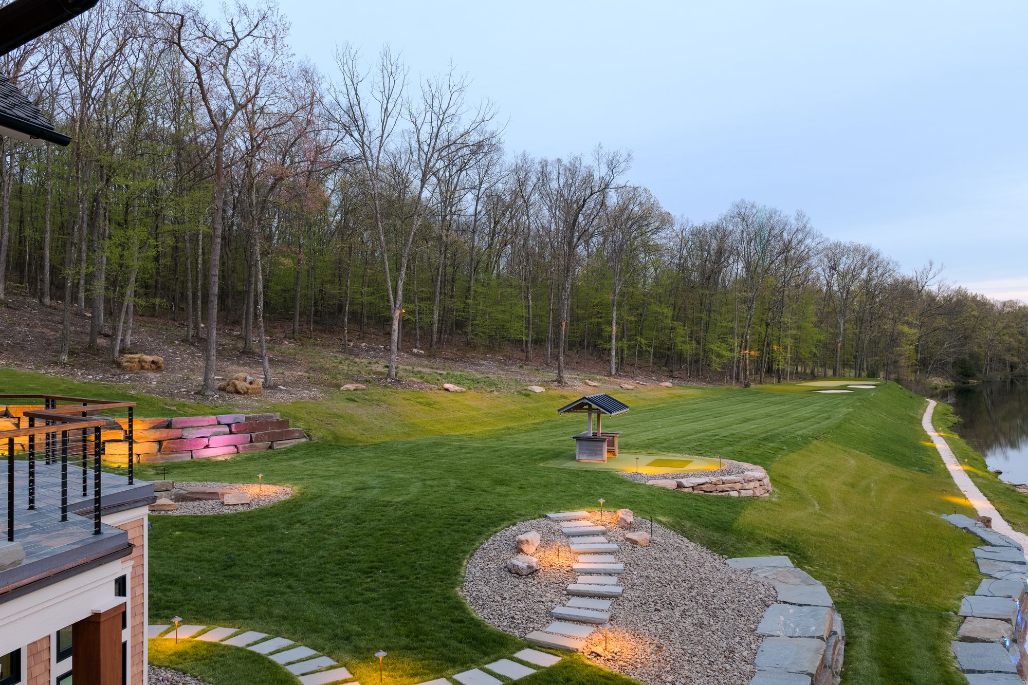 Lawn and lit stone walkways running down to the lake at dusk