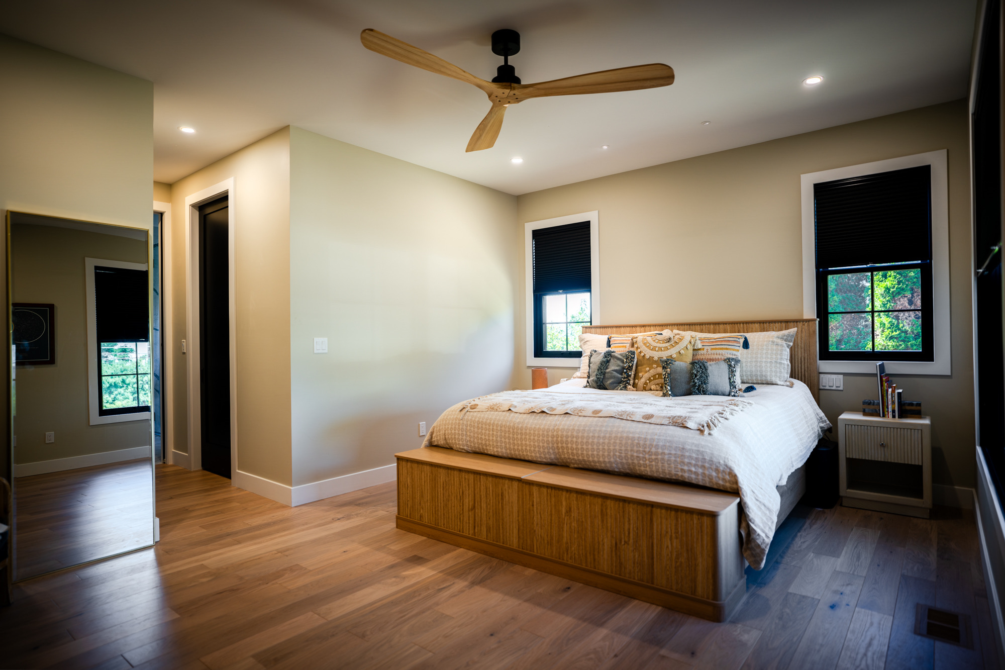 Bedroom with wide-plank floors, a wood ceiling fan and black-framed windows
