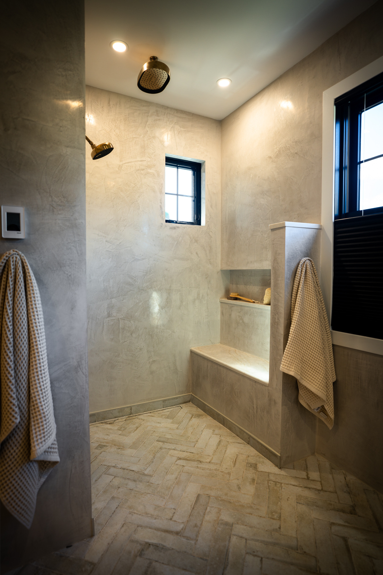 Walk-in shower in plaster-look walls with a bench and herringbone floor
