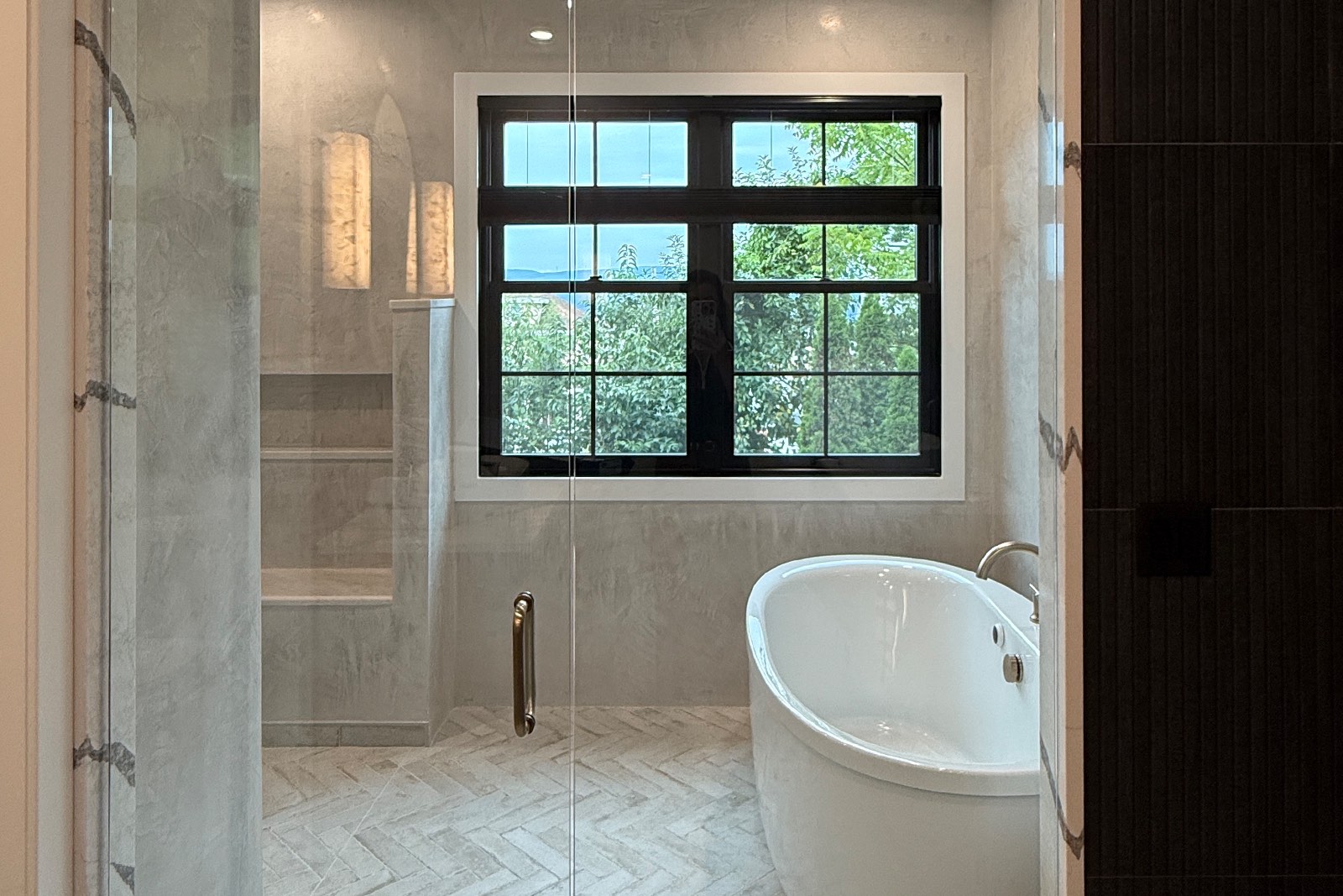 A black-framed double window above a freestanding tub, seen through a glass shower door