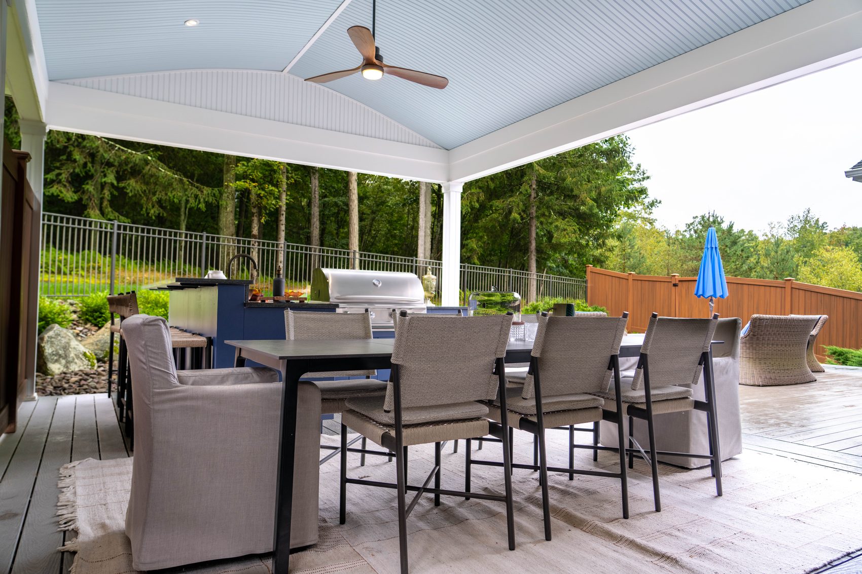 Outdoor dining on a covered composite deck with a ceiling fan and a grill beyond