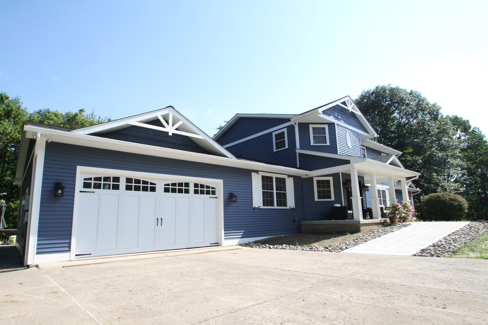 A blue house with new windows, a covered entry and carriage garage doors