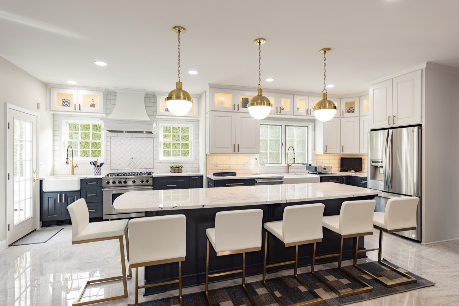 Remodeled kitchen with brass pendant lights over a navy island