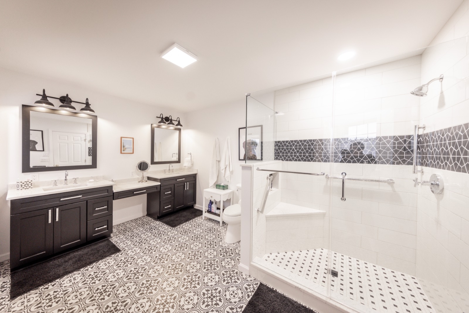 A bathroom with a walk-in glass shower, a built-in bench, a double vanity and a seated makeup counter