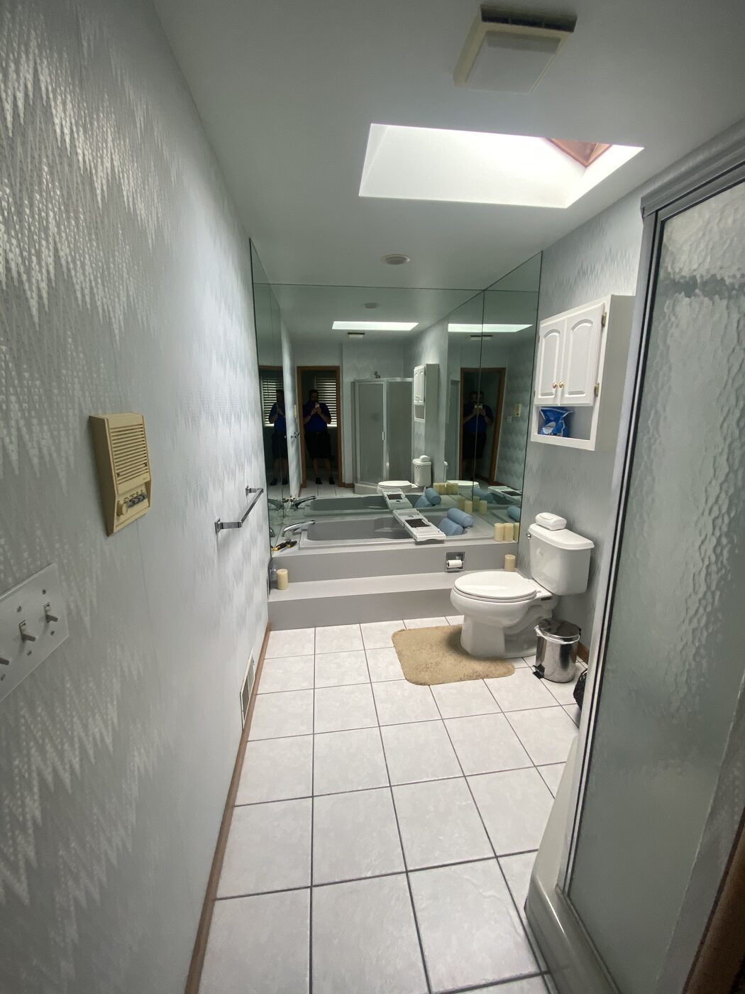 A bathroom before remodeling: dated green wall tile, a cramped tub and a low dropped ceiling