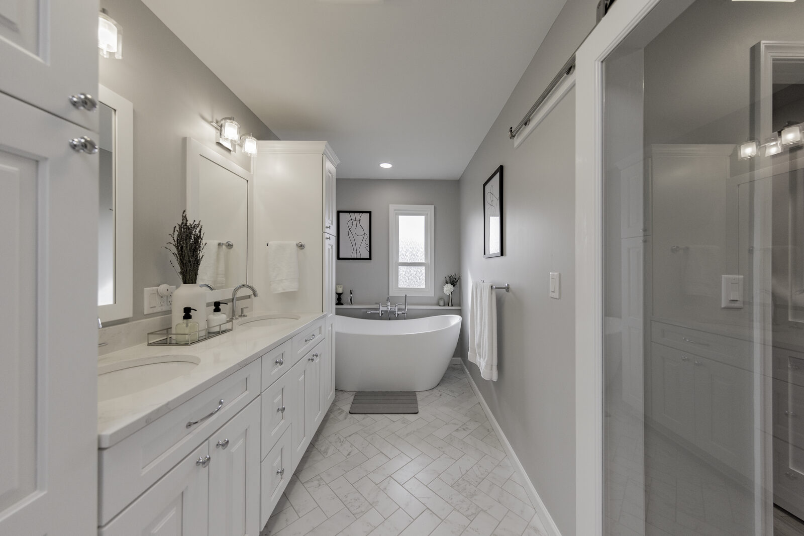 The same bathroom after remodeling: white cabinetry, a freestanding tub and a skylight over the vanity