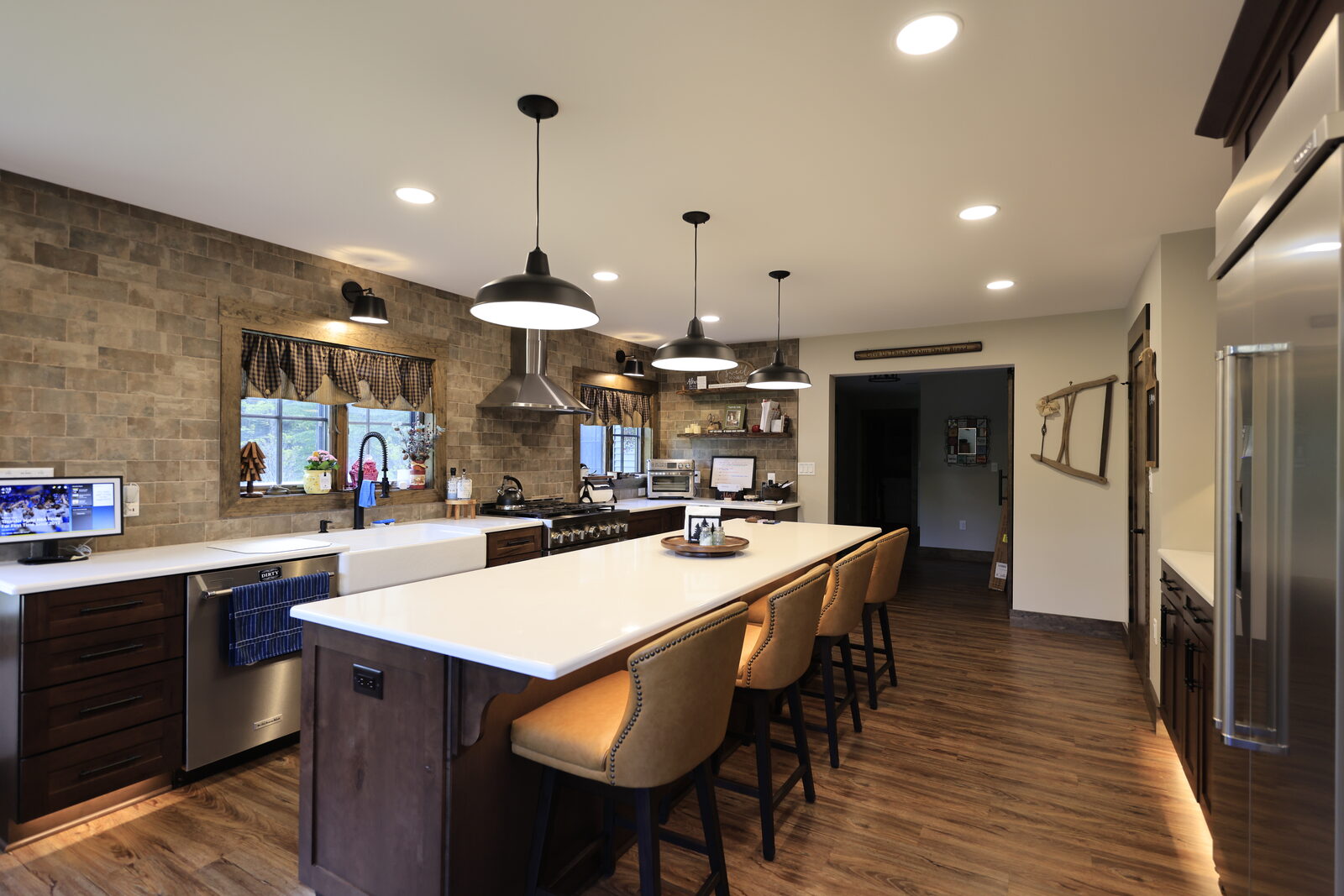 A kitchen with a full-height stone backsplash wall, white counters and a long wood island