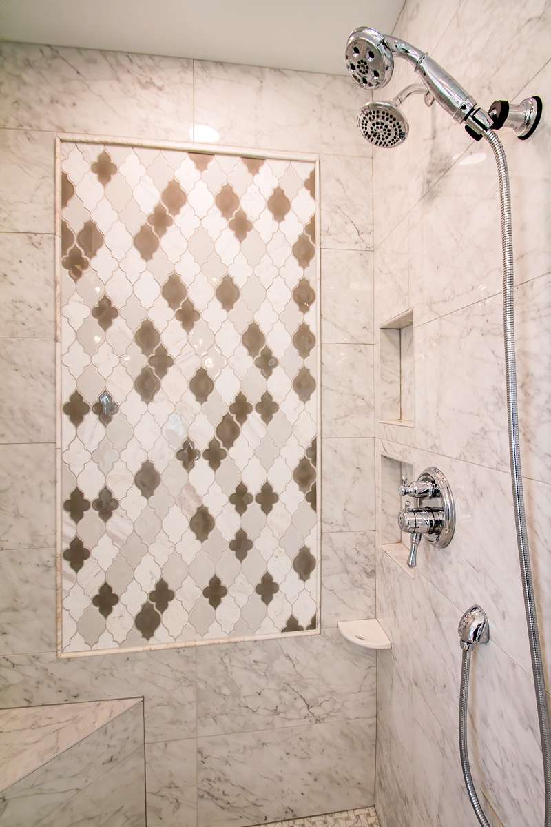 Marble tile shower walls with a diamond mosaic panel