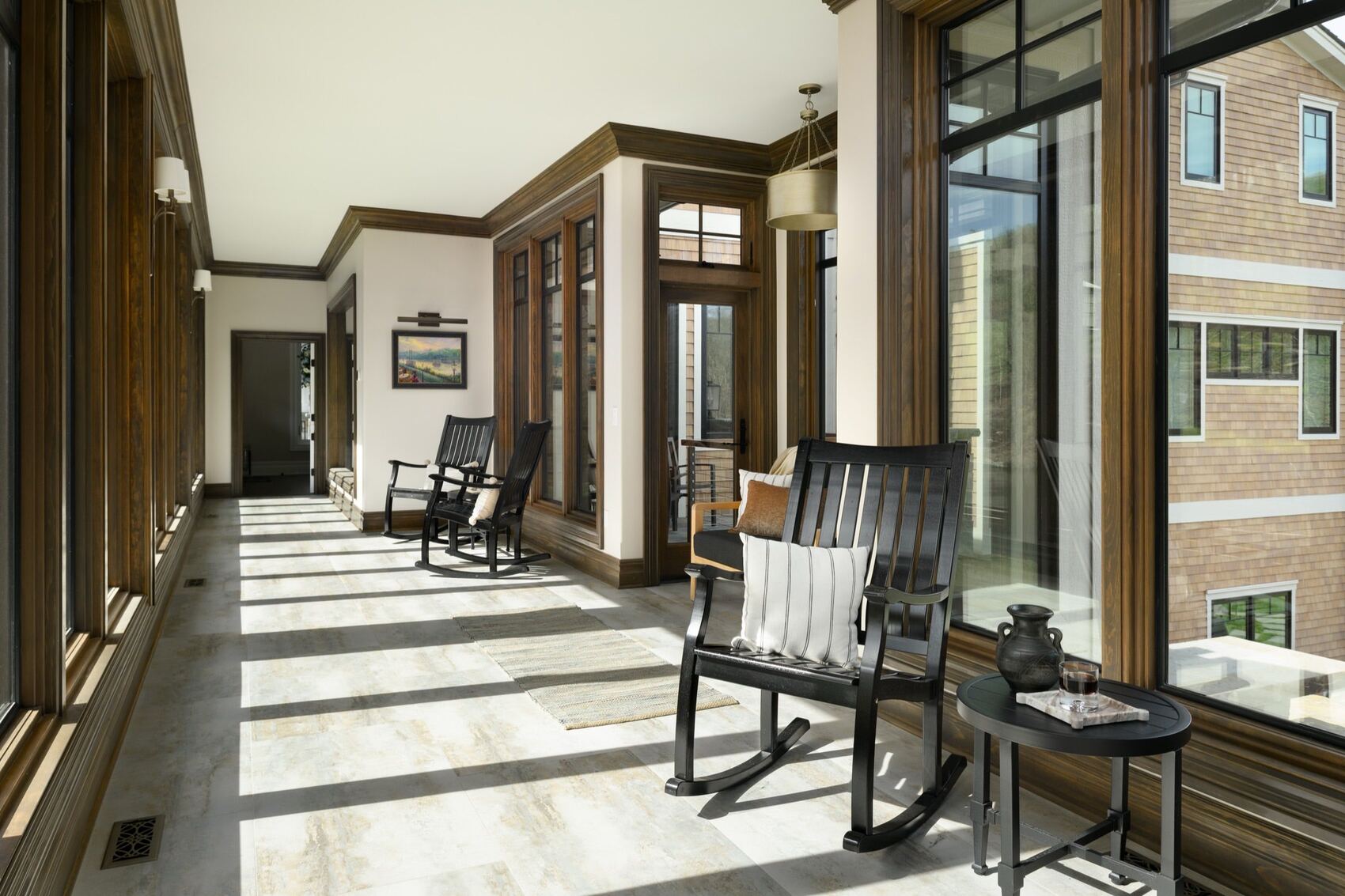 A screened porch with floor-to-ceiling glass and rocking chairs