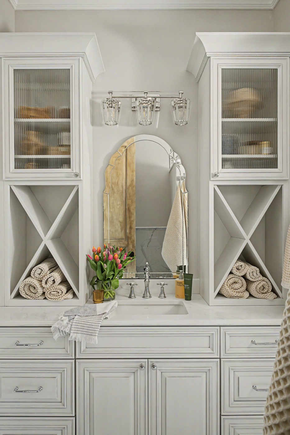 A built-in bathroom vanity with glass-front cabinets