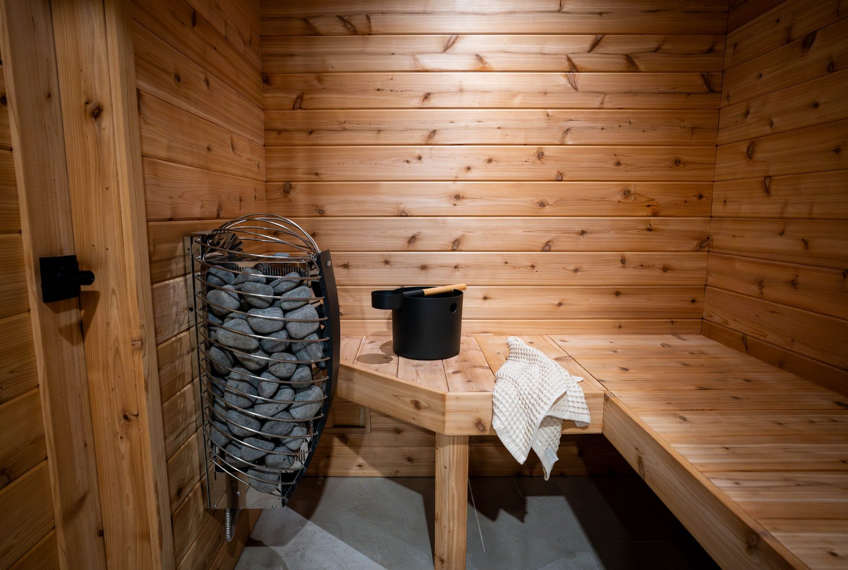 A cedar sauna with a stone heater and a wooden bench